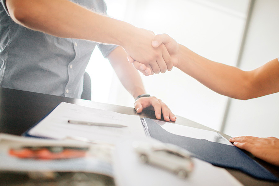 About Our Brokerage - Closeup View of Insurance Agent Shaking Hands with a Client with Views of Paperwork on the Table