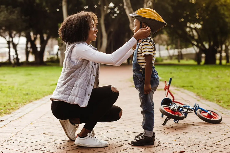 Group-Voluntary-Supplemental-Life-Insurance-Mother-Placing-a-Protective-Helmet-on-Her-Son-Before-Riding-a-Bike-in-the-Park-on-a-Sunny-Day